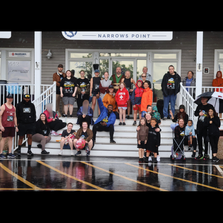Group of 5K participants gathered on the steps of Narrows Point Marina, smiling in rain gear after the event.