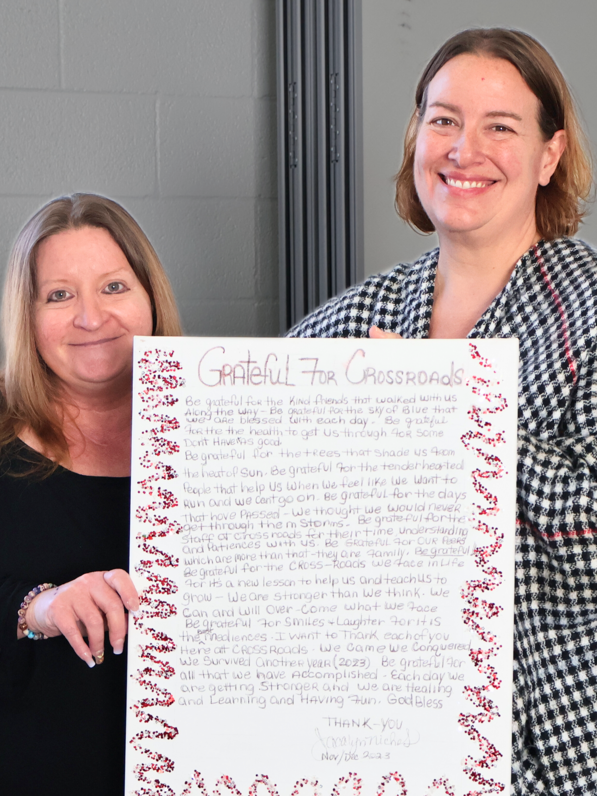 Two women holding a handwritten gratitude poster at a Crossroads Community and Corsica River recovery event