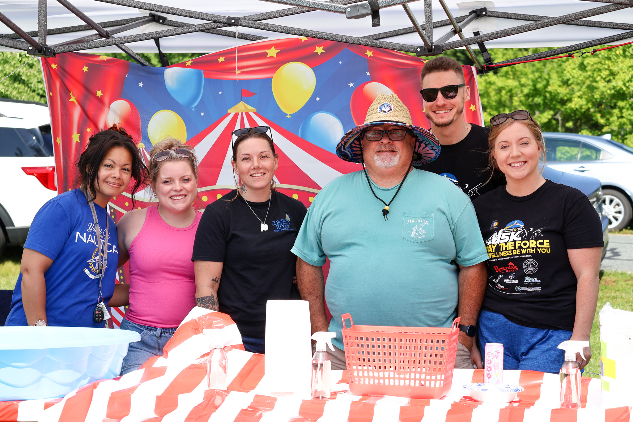 Group of Crossroads Community and Corsica River staff smiling at a carnival-themed booth during community wellness event