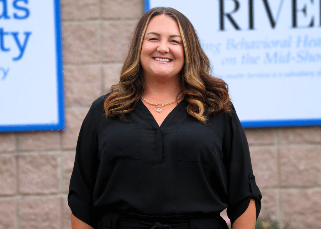 Kelsey Horney, HR Director at Crossroads Community and Corsica River Mental Health Services, smiling outside in front of organizational signage.